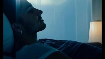 Soft moonlight streaming through a window, camera slowly zooms toward a person resting in bed, their face serene and illuminated by the faint glow of a nightlight video