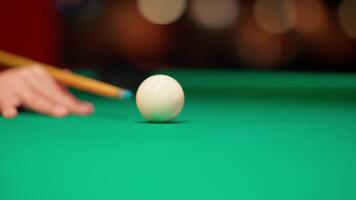 A person's hand is holding a cue stick on a pool table video