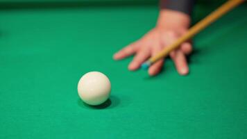 A person holding a cue stick and a ball on a pool table video