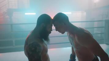 Two men in a boxing ring with one of them looking at the other video