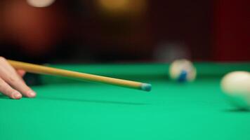 A person's hand is holding a cue stick on a pool table video