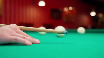 A person's hand is holding a cue stick on a pool table video