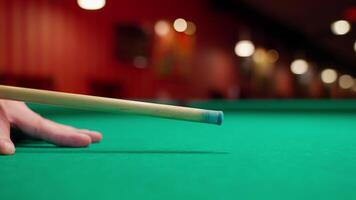 A person's hand holding a cue stick on a pool table video