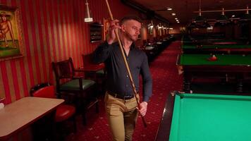 A man holding a cue stick in front of a pool table video