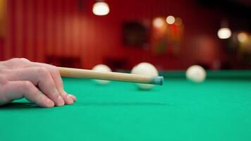 A person's hand holding a cue stick on a pool table video