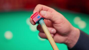 A person holding a red and white stick on a pool table video