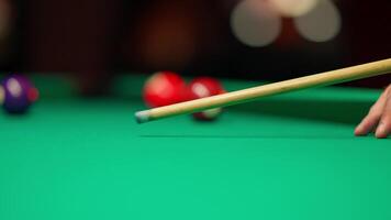 A person's hand is holding a cue stick on a pool table video