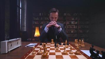 A man in a suit is playing chess on a table video