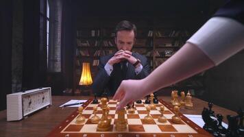 A man in a suit is playing chess with another person video