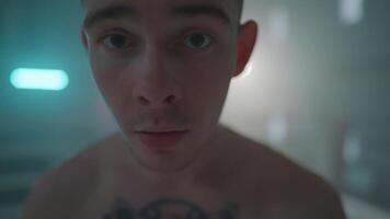 A man with a tattoo on his chest looks into the camera video