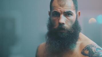A man with a beard and tattoos standing in front of a camera video