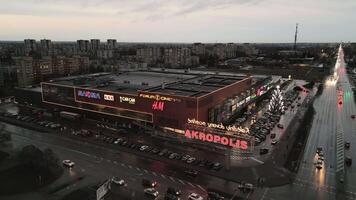 Siauliai, Lithuania - 19th november, 2024- aerial static Popular lithuanian shopping mall Akropolis with Illuminated Xmas tree and customers go shopping. Black friday winter celebrations shopping boom video