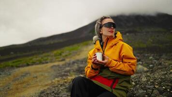 Woman Tourist Sitting By Herself On Mountainside, Taking Break And Sipping Tea, Exploring Mountains video