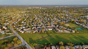 Suburban Neighborhood with Green Fields and Homes, Wide aerial view of a peaceful suburban neighborhood with tree-lined streets, green fields, and rows of houses under soft sunlight. video