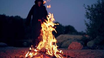 Man in cassocks by the fire. Monk in brown cloaks of the order of St. Francis by the fire video