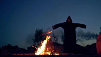 Concept of Halloween and witchcraft. Black witch in a mantle stays in front of fire video