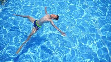Boy relaxing in pool. Boy swimming and playing in a pool video