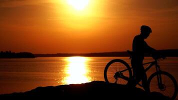 Biker riding on bicycle on hill. Cyclist with mountain bike on rocky trail at sunset video