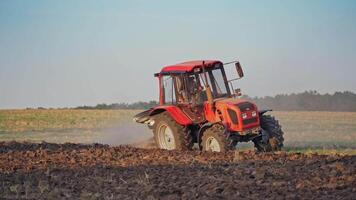 Red tractor in a field. Tractor ploughing a field with a trail of dust behind it video