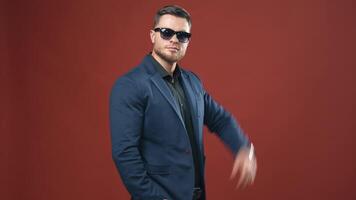Portrait of handsome businessman. Stylish man taking off black glasses on the studio background. Smiling man in dark blue suit posing on camera. video