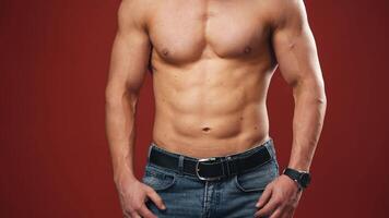 Moving chest of muscular man's body. Topless bodybuilder in the studio on the red background. Close-up. video