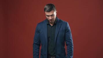 Handsome man in stylish suit. Portrait of young businessman in the red studio. Smiling bearded man in black shirt and blue jacket looking at camera. video
