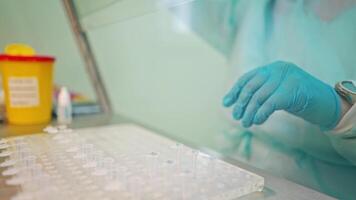 Preparation for blood test. Doctor hand taking a blood sample tube from a rack with machines of analysis in the lab background video