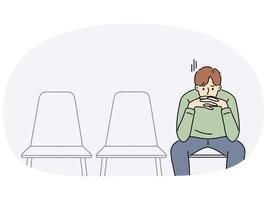 Sad man is waiting for start of interview, sitting in office corridor with empty chairs vector