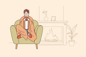 Man feels comfort and harmony sitting by fireplace with blanket on shoulders and cup of hot coffee vector
