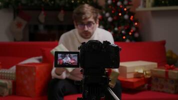 Camera focus man vlogger filming new vlog with professional camera at home for Christmas. video