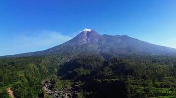 Panoramic aerial drone footage of Mount Merapi from a short distance with a beautiful view on a summer morning. 4k landscape of active volcano in detail with green forest in front. video