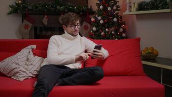 A man on a call on the phone in a Chrismtas decorated scene. video