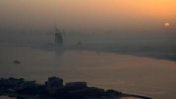 A city skyline with tall buildings in the background overlooks a body of water at sunset in Dubai from the Palm Jumeirah observation point video