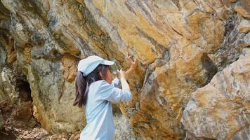 A girl examines rocks through a magnifying glass while exploring the nature of a forest on a sunny day. Outdoor ecology school lesson. video