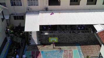 An aerial view of a school courtyard with a basketball court video