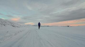 Aerial drone view of young man jogging outdoors with snowy mountains in the background. Healthy running and exercise concept outdoors, high-speed drone fvp shooting, slow motion video
