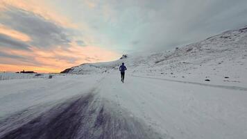 Aerial drone view of young man jogging outdoors with snowy mountains in the background. Healthy running and exercise concept outdoors, high-speed drone fvp shooting, slow motion video