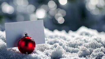 Festive red christmas ornament with blank card on snowy surface in winter wonderland, merry christmas and happy new year concept video