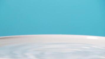 A white bowl with water on a blue background video