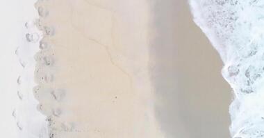 aerial overhead footage with drone over the coast of an uncrowded beach with the waves coming to shore video
