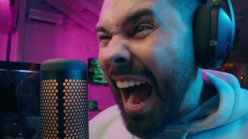 Close up happy laughing Caucasian streamer male influencer man blogger talking microphone device at home guy vlogger gamer shouting playing computer game online scream record blog cyber sport addicted video