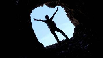 Silhouette of the girl raising arms in the cave video
