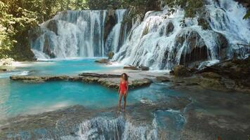 Woman enjoying on cascade waterfalls with turquoise water in Sulawesi, aerial view video