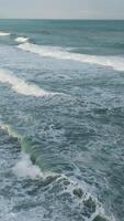 Aerial view capturing wind waves crashing fluidly on a freezing ocean beach video