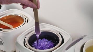 A person is using a spoon to stir purple liquid in a container video