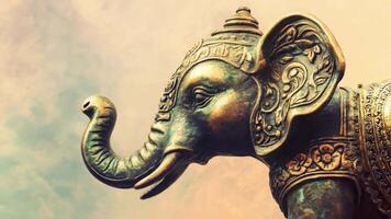 A beautifully crafted brass elephant sculpture showcases detailed carvings, highlighting its trunk and ear, with a pastel sky in the background as twilight sets in. video