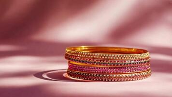 A set of vibrant bangles lies gracefully on a soft pink surface, reflecting light and highlighting their intricate patterns and sparkling details, creating an elegant display. video