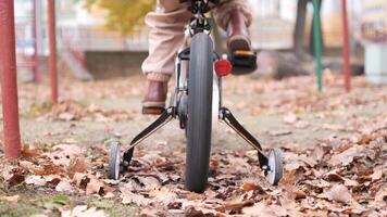 A child gets stuck on a bicycle with training wheels for riding a bike. The child pedals the bike but stays in place. A girl learns to ride a bike video