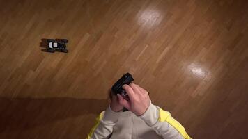 POV First-person view of a person holding a remote control and maneuvering a radio-controlled car on a polished parquet floor, creating a playful and engaging scene video