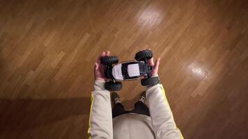 First-person view of a person holding a radio-controlled car indoors on a wooden floor, ready to play and have fun. video